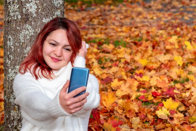 Smiling woman taking selfie against tree in autumn