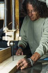 Mature male woodworker cutting plank with band saw
