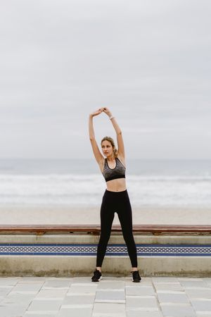Woman in sports clothing stretching before exercise at seaside