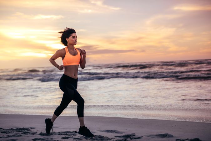 Woman in running outfit sprinting on the sea shore