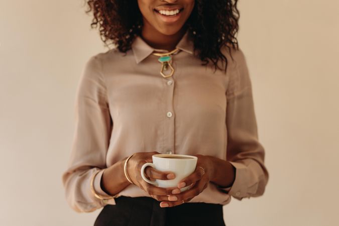 Smiling Black woman in blouse holding a mug