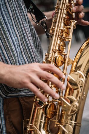 Crop view of male saxophonist playing sax in the street