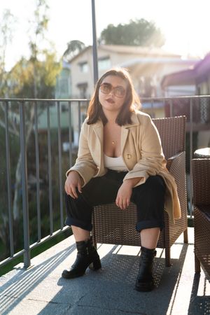 Young woman sitting on patio chair leaning forward looking at camera