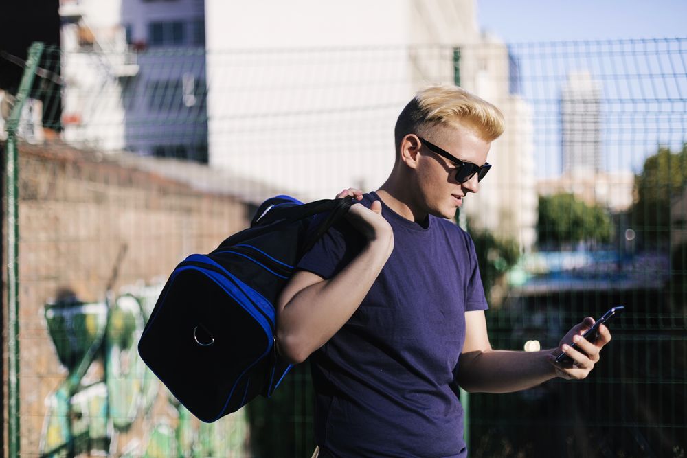 Side view of blond male using a cell phone on the street