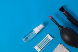 Top view of lens cleaning kit on blue table with copy space