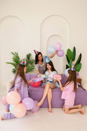 Family birthday celebration with mother and three daughters sharing gifts