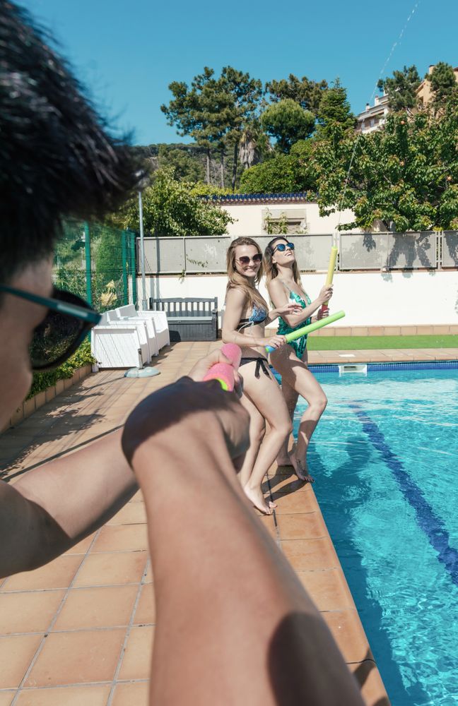 Friends playing with water pistols in the pool