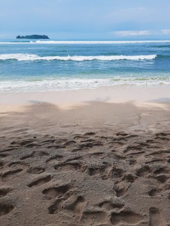 Footprints on sandy beach near ocean waves in Angso Duo Island, Pariaman, Indonesia