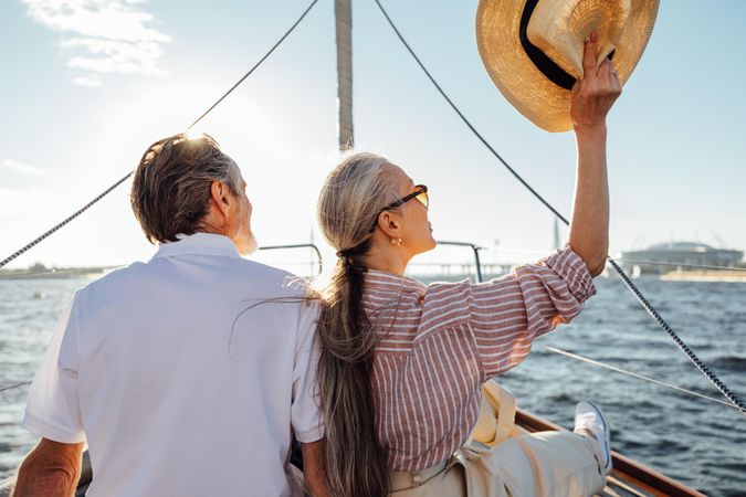 Back view of relaxed mature couple sitting on bow of yacht
