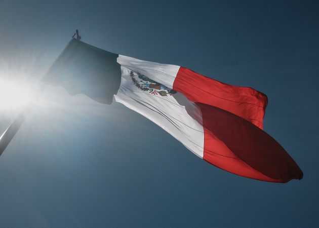 Looking up at Mexican flag against a blue sky