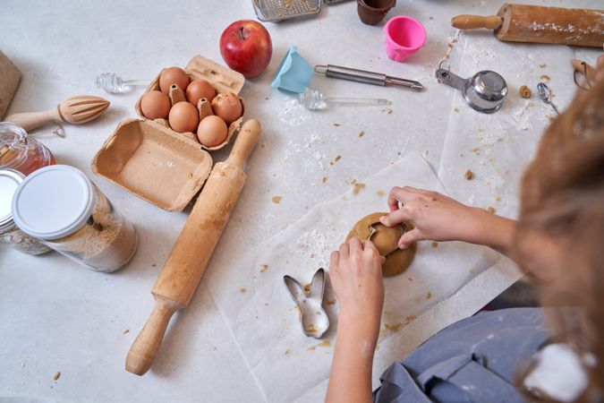 Crop kid preparing cookies on table