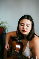 Close up of young Asian woman with eyes closed playing guitar