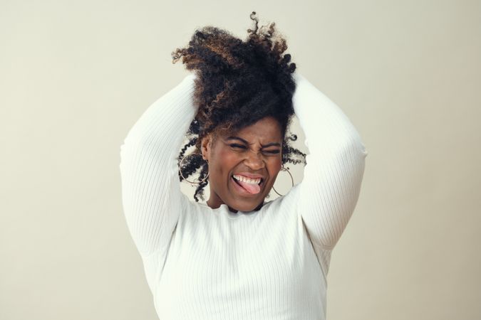 Portrait of joyful Black woman running her hands through her hair