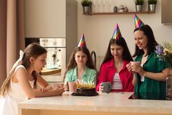 Family of four with party hats celebrating birthday with cake