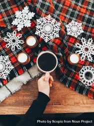Person holding a coffee mug over a wooden table with christmas decoration 0VLmO4
