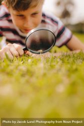Kid playing with magnifying glass outdoors 5qz7J4