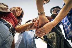 Low-angle view of a diverse group of friends stacking hands in a circle.