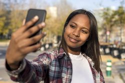Female taking selfie with park in background