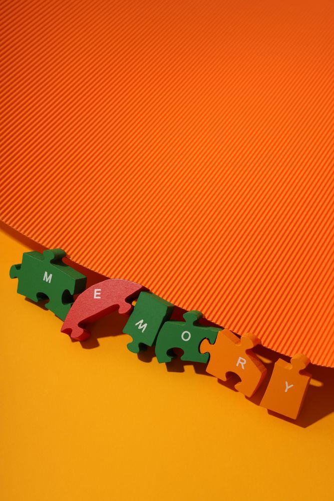 Orange duotone flat lay with puzzle pieces spelling out the word “Memory”