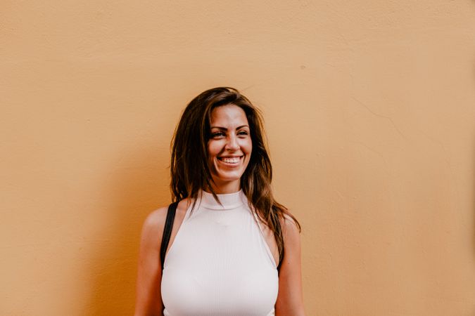 Young brunette standing against orange background