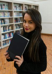 Woman standing along bookshelves and holding open book