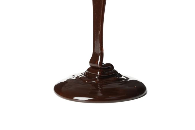 Melted chocolate is pouring, isolated on blank background