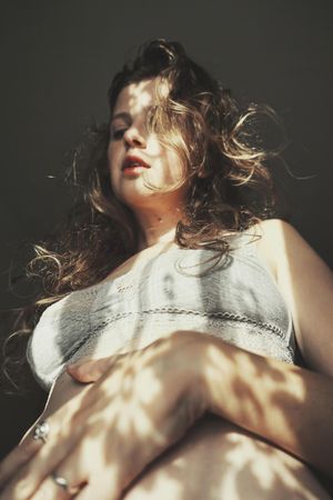 Low angle view of woman in gray bra with floral shadow from the window