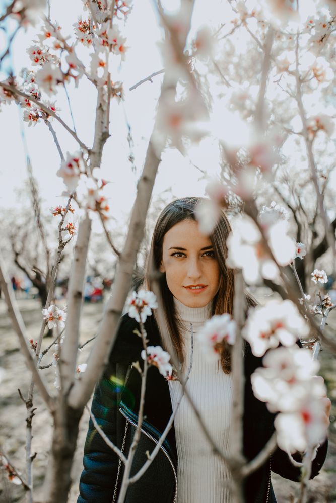 Young happy woman between trees in garden