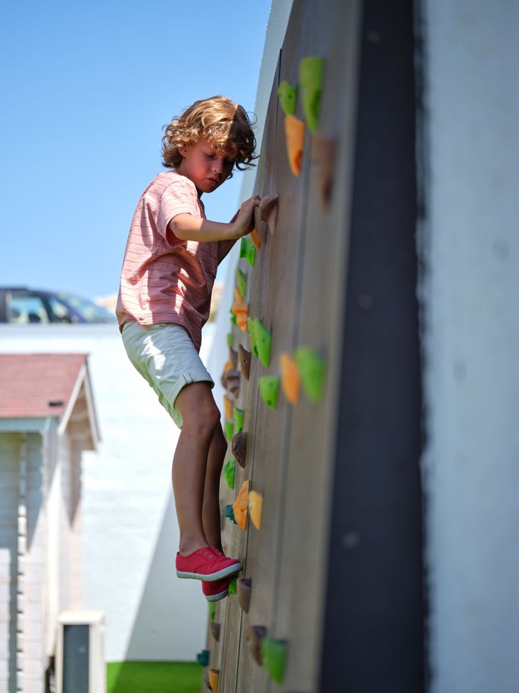 Little boy climbing rock wall outdoors