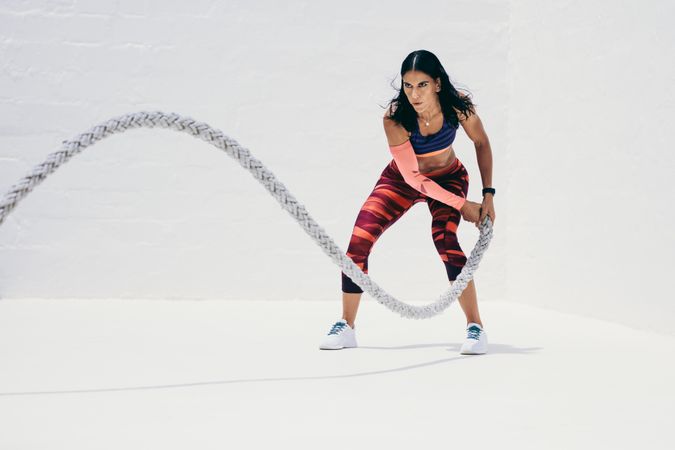 Fitness woman strength training using battle rope