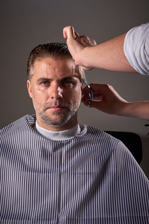 Faceless hairdresser cutting hair of man