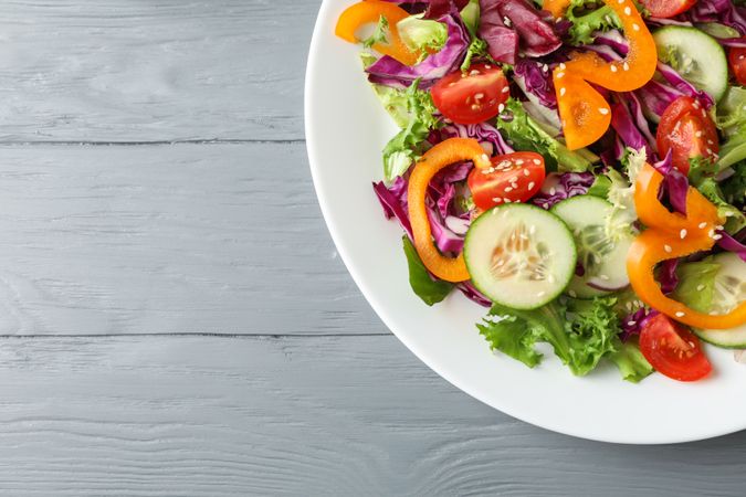 Plate with fresh salad on wooden background, space for text