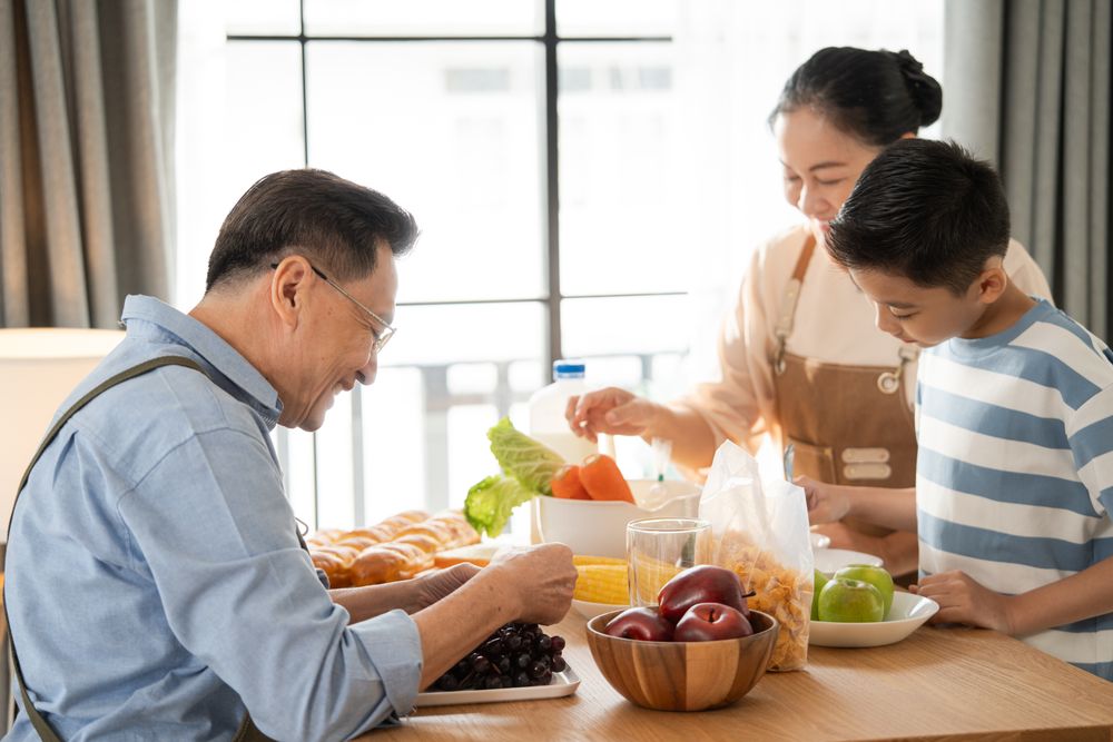 Asian grandparents support and help grandson cooking breakfast in the kitchen
