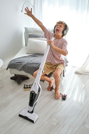 Boy with vacuum cleaner singing loudly