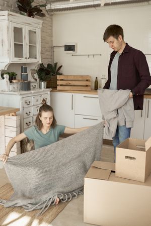 Cheerful couple unpacking boxes in light kitchen