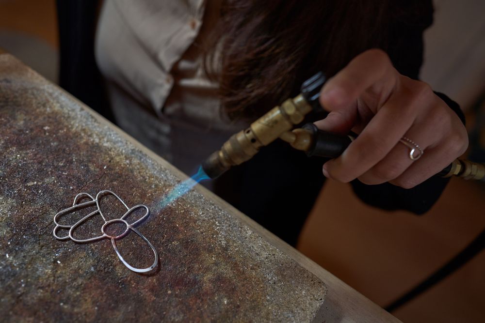 Woman making decorative handmade accessory with gas burner