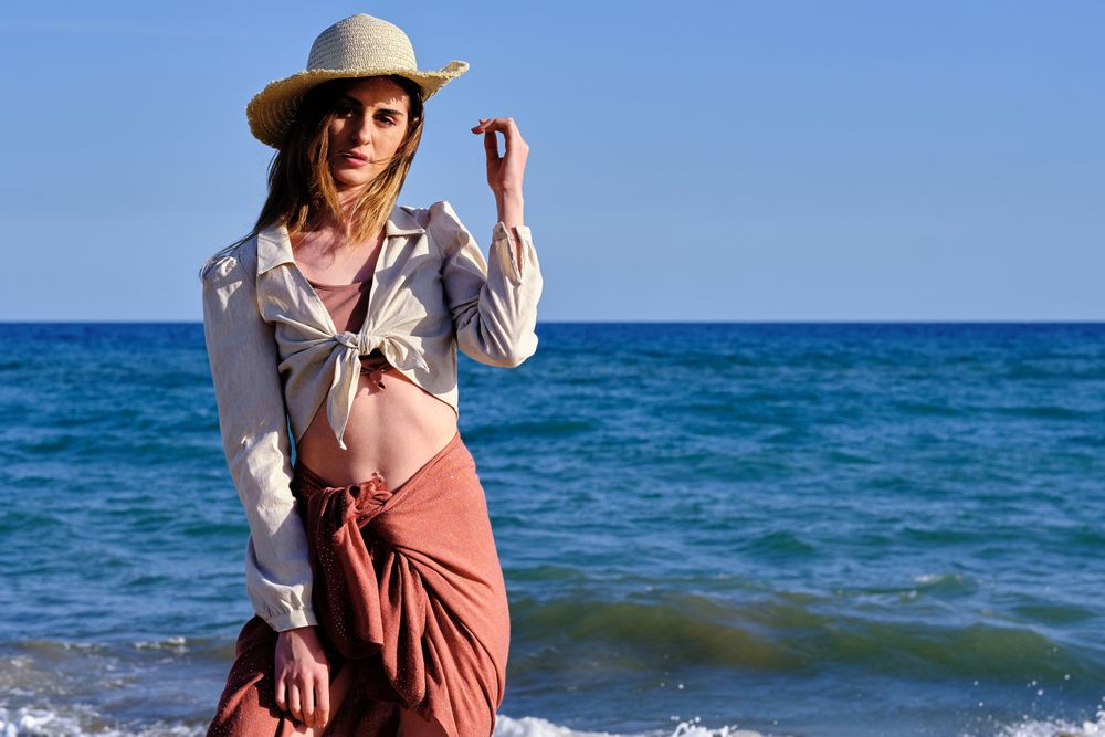 A fashion model with a hat at the beach before sunset
