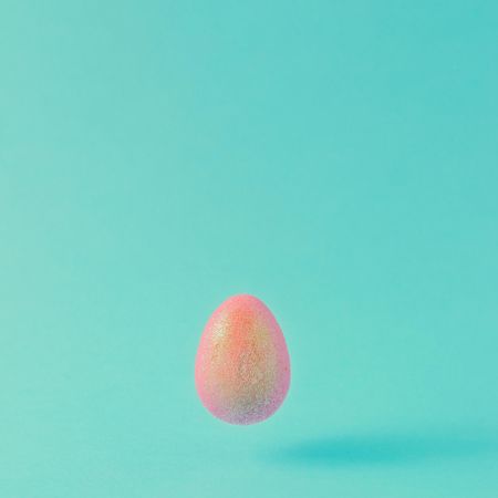 Pink glitter egg on teal background
