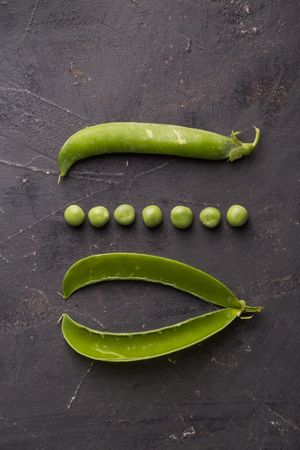 Fresh peas and pea pods on dark background