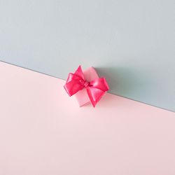 Gift box with pink ribbon on baby blue and baby pink background