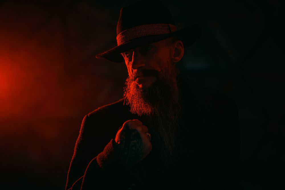 Portrait of middle aged man with fedora hat in red lit studio