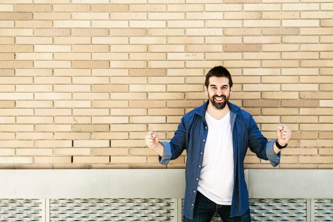 Man celebrating a win in front of brick wall