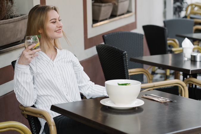 Young woman enjoying cocktail in terrace bar