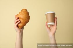 Female hands holding croissant and cup of coffee on beige background 5wJNR0