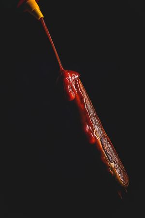 ketchup falling on grilled sausage