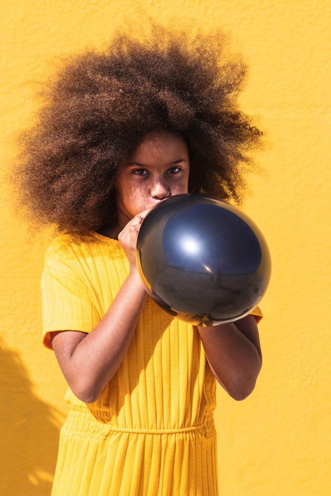 Black girl blowing party balloon
