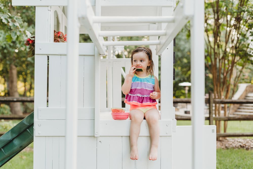 Young girl in colorful swimsuit eating watermelon