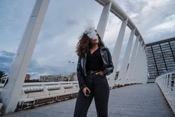 Stylish woman in jacket and jeans smoking on bridge