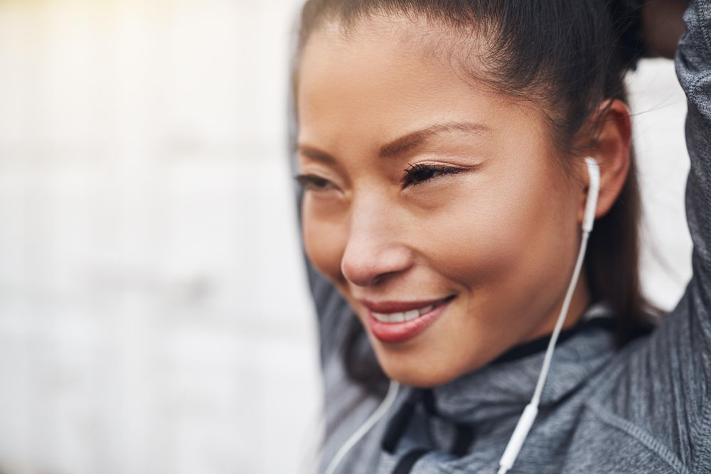 Happy woman stretching her biceps in workout gear