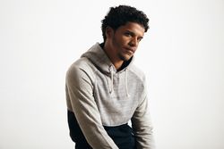 Man in grey hoodie looking thoughtfully into camera